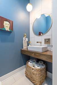 The half bath continues with a modern design featuring a floating counter, modern sink basin, a vertical tile featured wall, and modern lighting.