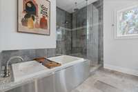 Clean and contemporary primary bathroom with jetted tub, glass shower with rainhead, double vanities, and toilet closet