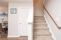 Door opens to the half bath. The carpeted stairs have a landing for easier access to upstairs