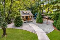 Shingle-style play cottage and tree fort platform nestled among tall pines and arborvitae Green Giants offering a magical forest-like feel. A kids outdoor dream space!