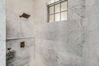 Exquisite solid marble walk-in shower in primary with rainfall shower faucet.