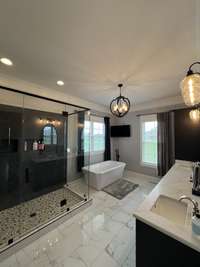 Owners on suite bathroom with TV hookup, custom glass shower and custom cabinetry with quartz countertops