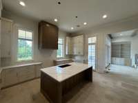 Spacious Gourmet Kitchen with reeded wood hood vent and reeded panels on each side of the island. *this house is under construction.  9/18/24