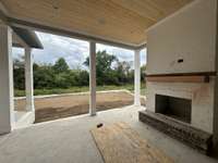 Spacious covered outdoor living area with wood-burning fireplace *this home is under construction  Built By: Insignia Homes Photo taken 9/18/24