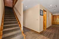 Bottom of the stairs in the walkout basement, offering a glimpse of the serene surroundings and inviting outdoor spaces.