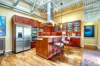 Granite island counters, an industrial-grade range hood, and all stainless appliances distinguish the attractive kitchen.