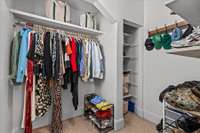 The primary closet is generously appointed with an extensive array of shelving and storage features, offering ample room to meticulously organize and store clothing and accessories, ensuring effortless accessibility and organization.