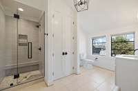 The bathroom showcases impeccable tile work The spacious shower stands as a focal point. With the added feature of a cleverly incorporated laundry space, this area exemplifies practicality without compromising on style.