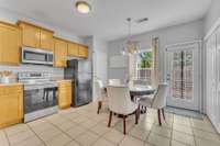 Large kitchen with tile flooring and mostly stainless steel appliances.