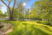 This expansive backyard boasts a delightful white picket fence, custom tool shed or playhouse, and beautiful landscaping!