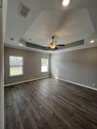 primary bedroom with trey ceiling, ceiling fan, led-lights in each corner of the trey, 2" faux wood blinds