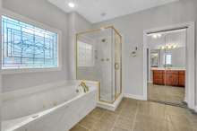 The primary bathroom with whirlpool tub and walk in shower.  An extra large walk in closet is behind the mirrored door.