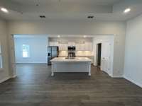 this view is looking from the great room into the kitchen. The kitchen features are: S/S appliances (all 4-pieces) under cabinet lights, tile backsplash, staggered cabinets, large island, 2 pantries (1 in the kitchen, 1 in the laundry room-