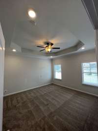 primary bedroom with tray ceiling, ceiling fan, led lights in each corner of tray, 2" faux window blinds