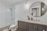 Stylish, renovated primary bath with glass-wall shower and fully tiled walls.