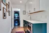 Around the corner from the kitchen is the butler station, another sink and more cabinets. Laundry room straight ahead closes and can be hidden.