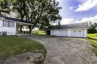 View of concrete parking area for garage and home.