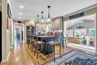 Renovated kitchen with island gas cooktop and microwave drawer looking into sunroom w/skylights.