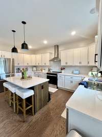 Kitchen w/white cabinets, quartz countertops, stainless steel appliances, Island w/bar seating, wood floors