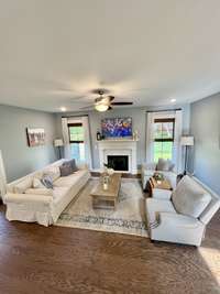 View of Living Room has gas fireplace,m ceiling fan, hardwood floor