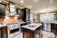 Brick backsplash, granite counters, and an island with sink for a seamless cooking experience