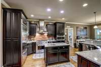 This is a chef's kitchen! Kitchen aid refrigerator, 6 burner gas cooktop stove,  built in Kitchen Aid refrigerator, eye catching stainless vent hood!