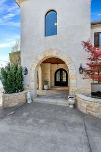 The courtyard winds to the front door by way of a block-stone arched entry & covered threshold w/ exterior lighting, perfect for receiving guests during inclement weather or after-hours. Note the attention to detail & abundance of healthy plantings.