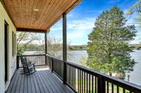Located just off the primary suite, this covered balcony is private & cozy. Accented by a tongue-&-groove ceiling, the balcony offers unobstructed views of the property, its healthy hardwoods, & the lake on all sides.