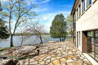 A flagstone patio wraps around one corner of the home, flat & stable, ideal for setting up an outdoor dining area for a large party or private event. Note how close the dock is to the home, just a skip & a hop from indoors to the lake.