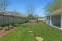 The backyard is fully irrigated with lush landscaping and stone walkway leading to 2 more patios.