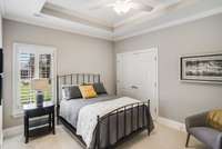 Secondary bedroom number two includes a tray ceiling, lush carpet, and a ceiling fan.