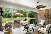 Screened porch leads to an oversized patio surrounded by lush landscaping.