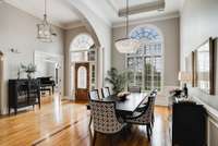 Another view showing the entrance and open dining room with tall ceilings a tray ceiling, new fixtures and sand-n-finish wood floors.  Notice the darker wood inlay in the dining area.