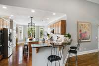 This kitchen is well appointed and complete with granite counters, a bar area for eating and socializing, stainless steel appliances, an island, cabinets with dovetailed drawers, and newer fixtures.