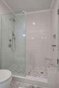 Primary bathroom walk-in shower with marble floors.