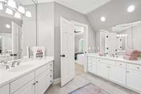 Double vanities and a separate tub and toilet area adjoin this space.