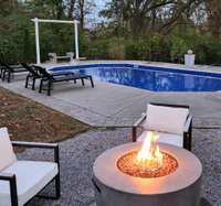 Relaxing poolside oasis with a cozy fire pit. Ideal for daytime lounging or evening gatherings.