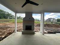 Spacious outdoor living area with wood-burning fireplace   *this home is under construction. Photo taken  5/4/24