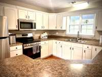 Beautiful white kitchen has all appliances, lots of cabinets, lots of counterspace PLUS area for bar stools for an eat on breakfast bar area.