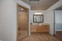 Large vanity, tiled floor and tiled shower.