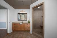 Large vanity, tiled floor and tiled shower.