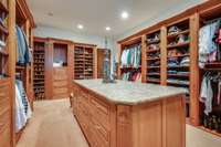 Organization made easy in this primary suite closet with lots of shelving and the large island for storage.