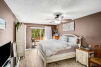 Large primary bedroom with sliding door to private deck space overlooking the lush woods.