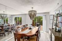 The formal dining room with statement light fixture is absolutely flooded with natural light thanks to strategically-placed mirrors and sliding door to the expansive deck that runs the entire length of the townhome.