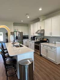 Tall White Cabinets with a gas range. Range hood exits outside of the House.