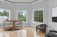 Sitting room above the foyer has a view of the surrounding lush landscape and pool area.