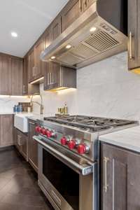 In this opulent kitchen, you'll find a Wolf stainless steel, dual fuel, six-burner gas range with striking red knobs and a surprising royal blue interior. Complementing this centerpiece is a Faber stainless steel wall hood with additional lighting.