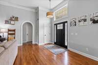 Freshly refinished beautiful front door with windows provide nicely sunlit room, charming crown molding, arched doorways and the neutral paint welcome any style.