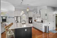 The classic white kitchen with staggered cabinets and continuous hardwood flooring creates the perfect hub of the home.