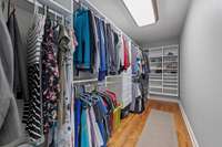 A primary closet adorned with custom built-ins, designed to optimize organization and storage. Each section is tailored to specific needs, with shelves, drawers, & hanging rods elegantly arranged to accommodate clothing, accessories, & shoes.